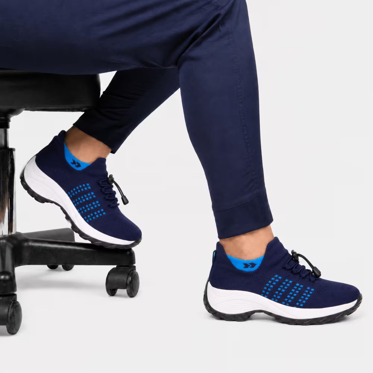 Navy blue knit lace-up sneakers on a person, white sole with blue grid detail